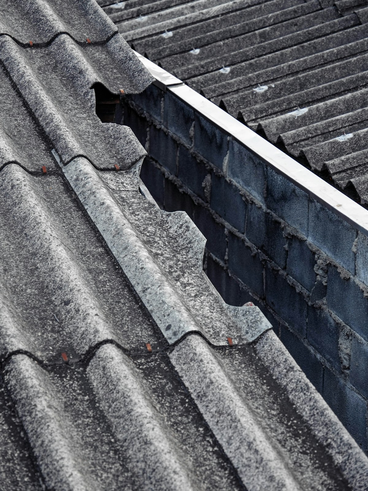 Roof before repair — damaged slate layers with displaced tiles and exposed verge where water was tracking in